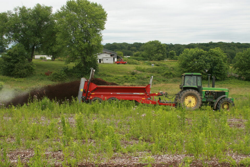 Vertical beater multi-product spreader applying a soil amendment to a field.